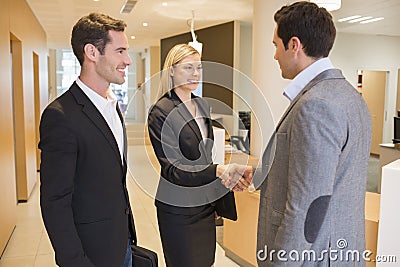 Smiling Business partners shaking hands in hall, lobby