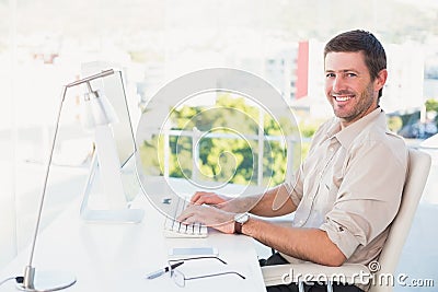 Smiling businessman using his computer at his desk