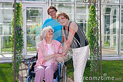 Smiling Care Takers for Old Patient on Wheel Chair.