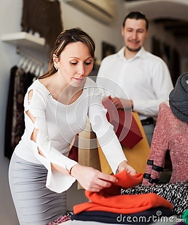 Smiling couple choosing clothes at boutique
