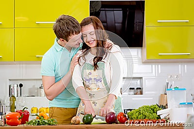 Smiling couple cooking apple pie at the kitchen at home