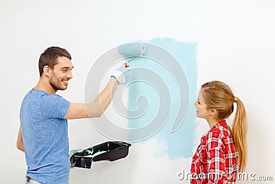 Smiling couple painting wall at home