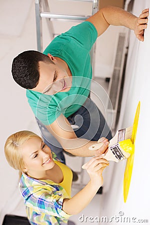 Smiling couple painting wall at home