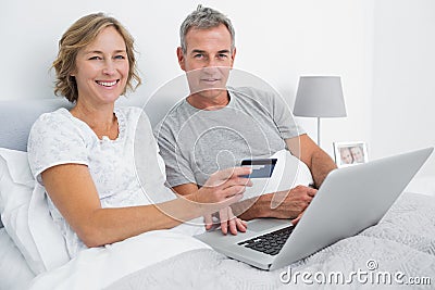 Smiling couple using their laptop to buy online