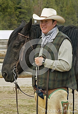 Smiling cowboy holding the head of his horse