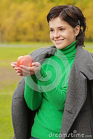 Smiling cute woman bites ripe apple