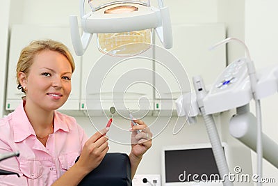 Smiling dentist sits in cabinet of dental clinic