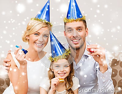 Smiling family in blue hats blowing favor horns