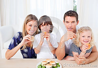 Smiling family eating burgers in the living room