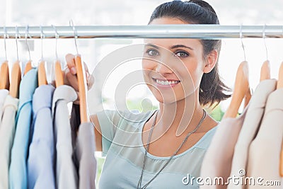 Smiling fashion designer looking at clothes