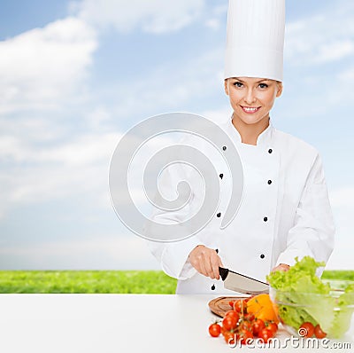 Smiling female chef chopping vegetables