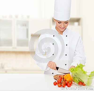 Smiling female chef chopping vegetables