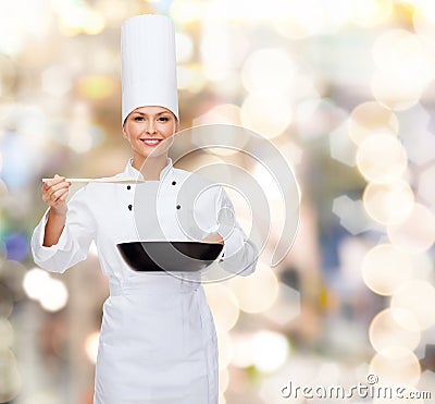 Smiling female chef with pan and spoon