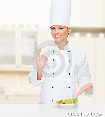 Smiling female chef with salad on plate