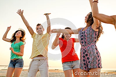 Smiling friends dancing on summer beach