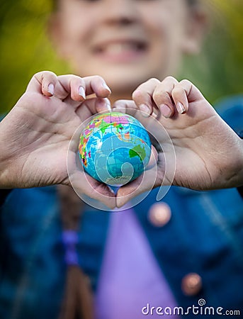 Smiling girl holding globe in hands folded in shape of heart