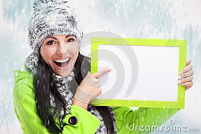 Smiling girl pointing at a blank board and around snowing