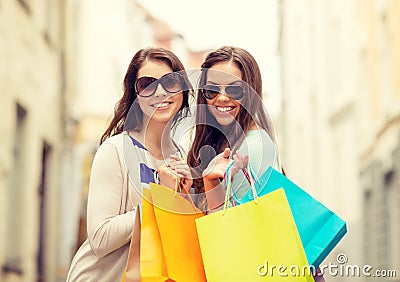 Smiling girls in sunglasses with shopping bags