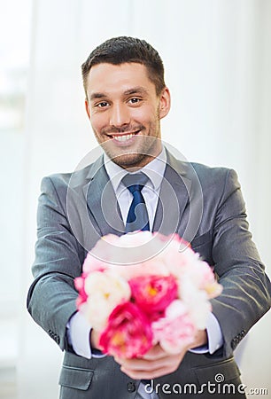 Smiling handsome man giving bouquet of flowers