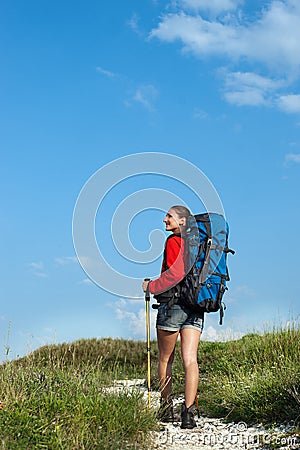 Smiling hiking young woman on the mountain trail