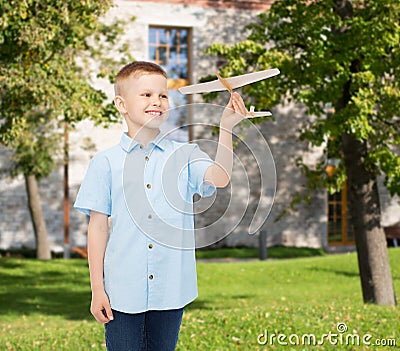 Smiling little boy holding a wooden airplane model