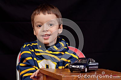Smiling little boy plays with toy car