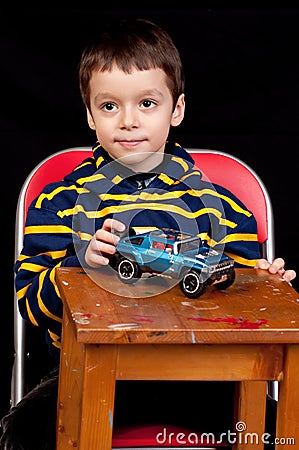 Smiling little boy plays with toy car