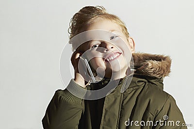 Smiling little boy talking on the cellphone. happy child in winter coat. fashion kids.children