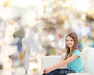 Smiling little girl with big fan at home