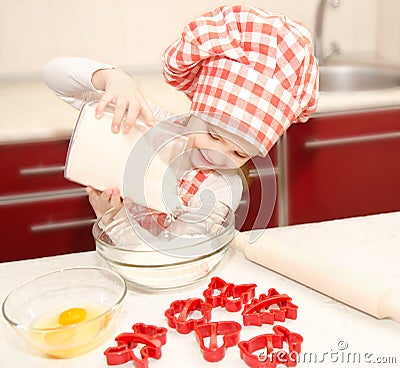 Smiling little girl with chef hat put flour for baking cookies