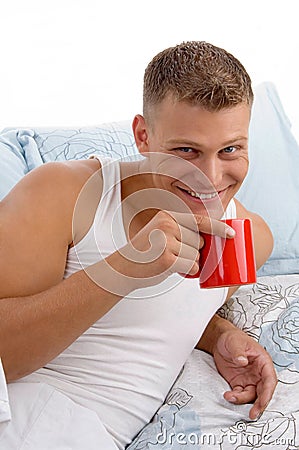 Smiling male drinking coffee in bed