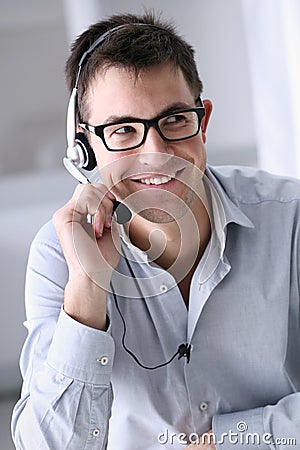 Smiling man with headphones in office, call center