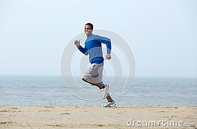 Smiling man jogging at the beach