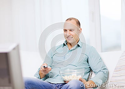 Smiling man with popcorn watching movie at home