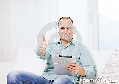 Smiling man with tablet pc and headphones at home