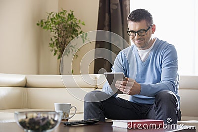 Smiling man using tablet PC at home