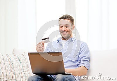 Smiling man working with laptop and credit card