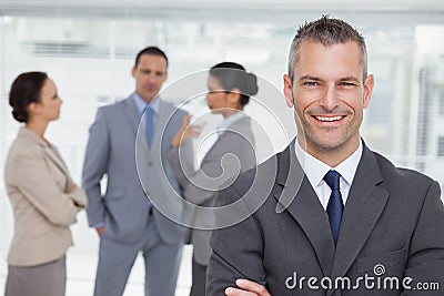 Smiling manager posing with employees in background