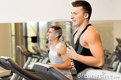 Smiling men exercising on treadmill in gym