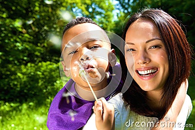 Smiling mother with son blowing dandelion