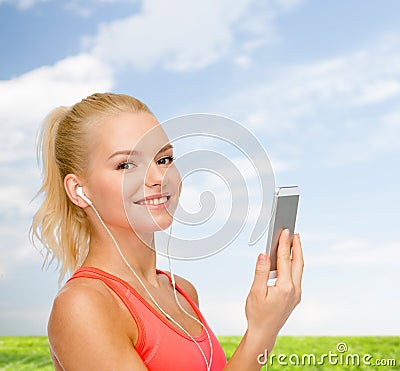 Smiling sporty woman with smartphone and earphones