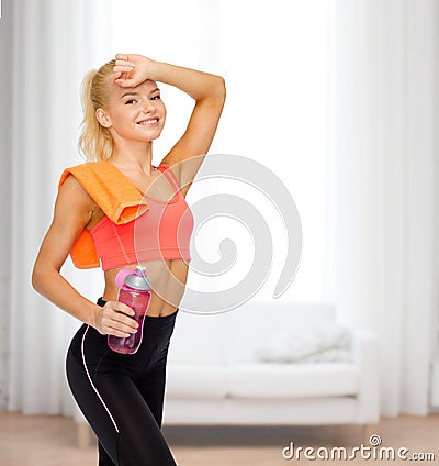 Smiling sporty woman with towel and water bottle