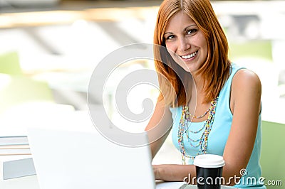 Smiling student girl with laptop at college