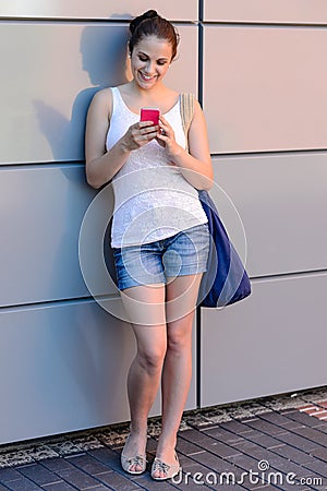 Smiling student girl using mobile phone college