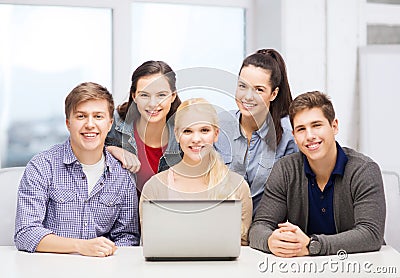 Smiling students with laptop at school