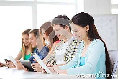 Smiling students with tablet pc at school