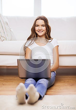 Smiling teenage girl with laptop computer at home