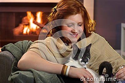 Smiling teenage girl loving her cat at home