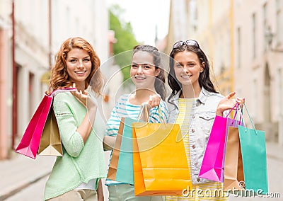 Smiling teenage girls with shopping bags on street