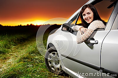 Smiling woman in the car at sunset